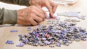 The man playing jigsaw puzzle game (focus at heap of jigsaw)