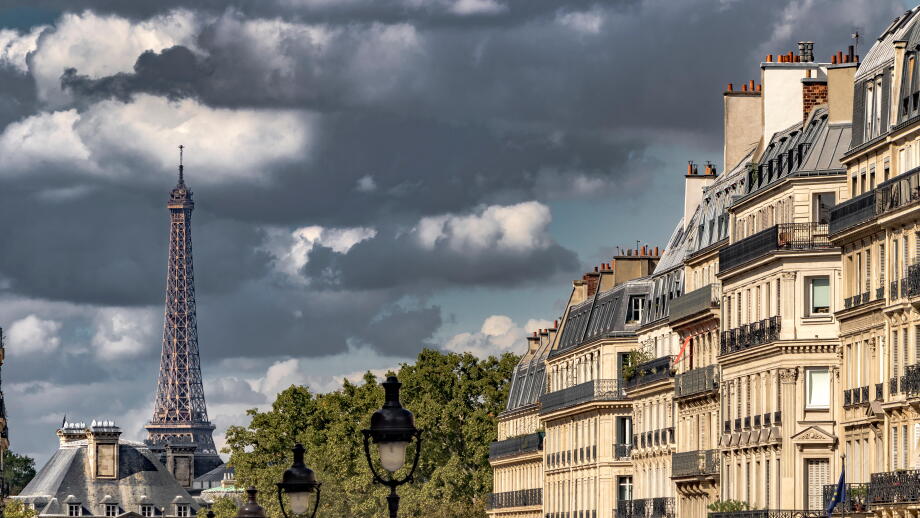 Dark clouds surround  The Eiffel Tower as seen  from Rue Soufflot , a street lined with impressive apartment buildings ,Paris ,France