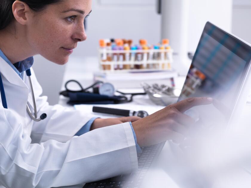 Doctor accessing a patients details using a touch screen computer in the clinic