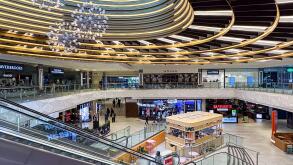 Modern multi-level retail atrium at Manchester Arndale Shopping Centre in Manchester, UK with glass balustrades and circular ceiling feature.