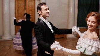 Portrait of smiling gentleman wearing classic tailcoat dancing with young lady during debutante ball in palace, copy space