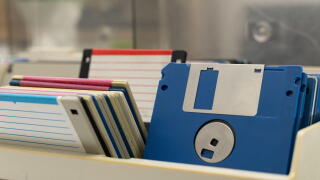A box of old 3.5-inch floppy disks, colorful floppy disks for 8-bit computers from the 1990s, a collection of old computer games on floppy disks, the