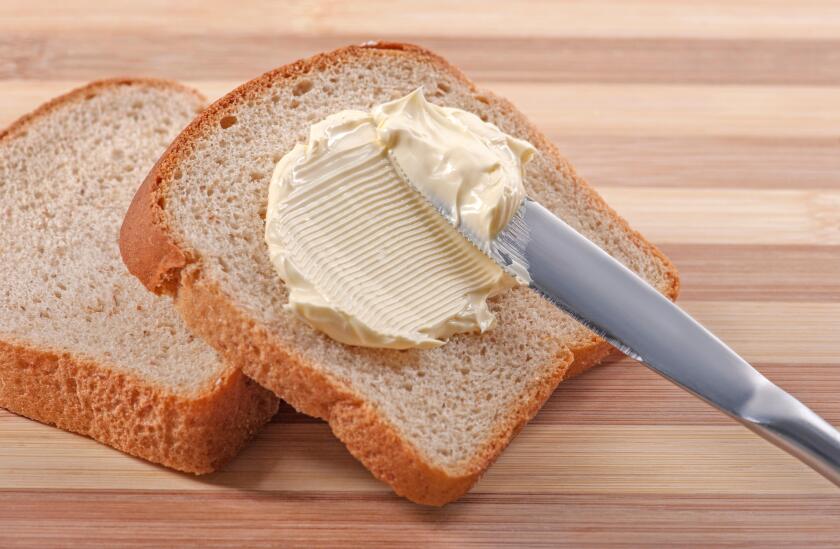 A knife spreading butter on wheat bread