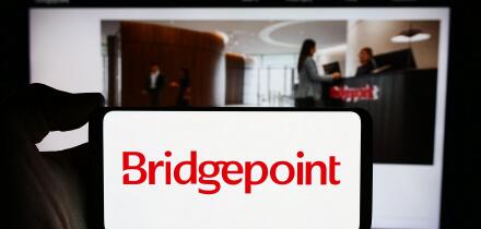 Person holding cellphone with logo of British investment company Bridgepoint Group plc in front of business webpage. Focus on phone display.