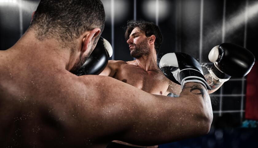 Boxer punches his opponent during boxing competition