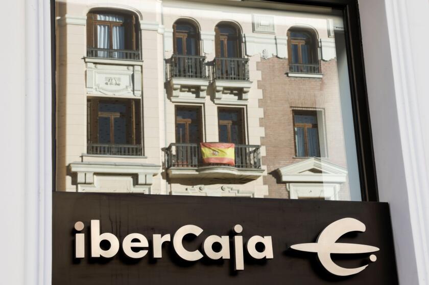 A Spanish flag hanging on a balcony is reflected in the glass of Ibercaja bank branch in Madrid, Spain, February 1, 2022. REUTERS/Juan Medina