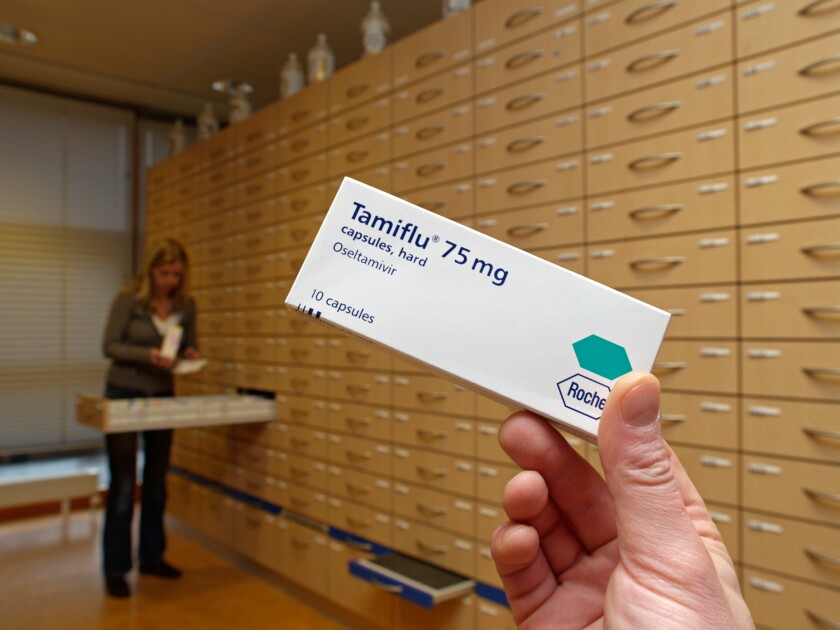 Hand holding Tamiflu medicine box in pharmacy Roche bird flu