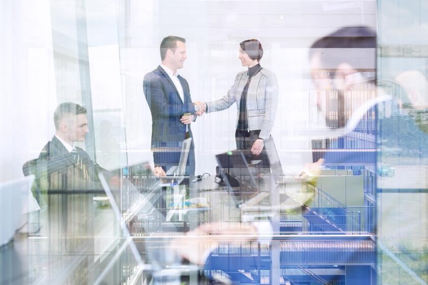 Business people shaking hands in moder corporate office.