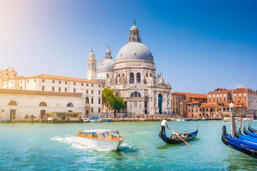 Traditional Gondola and boat on Canal Grande with historic Basilica di Santa Maria della Salute in the background, Venice, Italy