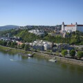 Bratislava Castle and the Old Town skyline over the Danube River, with bridge traffic and city landmarks on a clear day