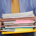 Overworked Businessman Carrying a Stack of Paperwork. Close Up.