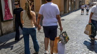 Rome, Italy. July 4, 2026, Rome, Italy: The man of a tourist couple carries three paper bags after purchasing on the day the summer sales begin in Rome. End-of-season summer sales began today in all Italian regions, with the exception of the autonomous pr