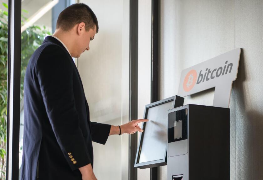 Young businessman buying cryptocurrency on ATM machine for buying and selling cryptocurrency.