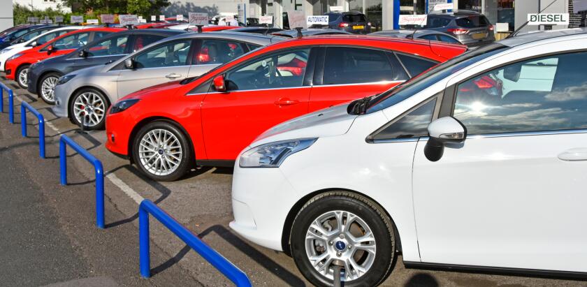 Ford car dealership business edge of pavement forecourt display of row of second hand used cars for sale dealer name removed Essex England UK