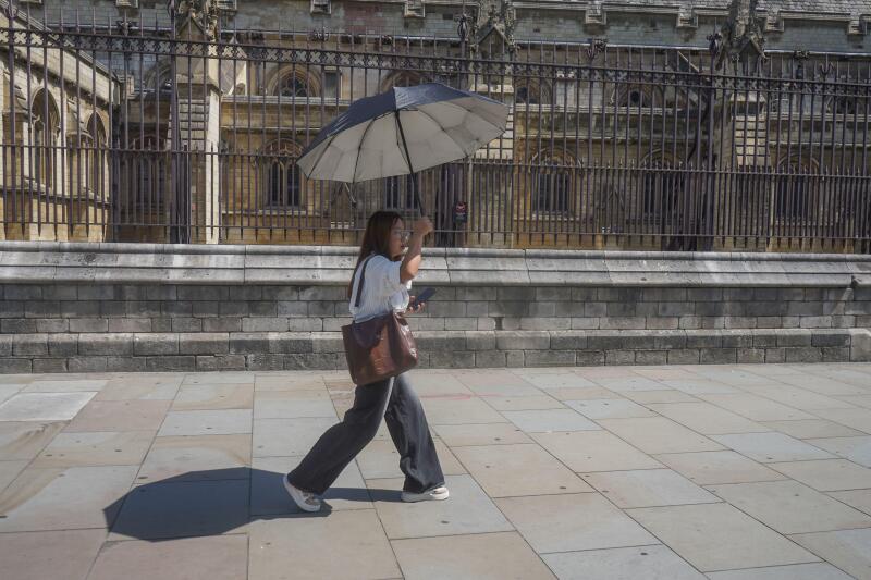 UK Heatwave: 22 June 2026  A pedestrian in Westminster shelters with an umbrella on hot sweltering day in London