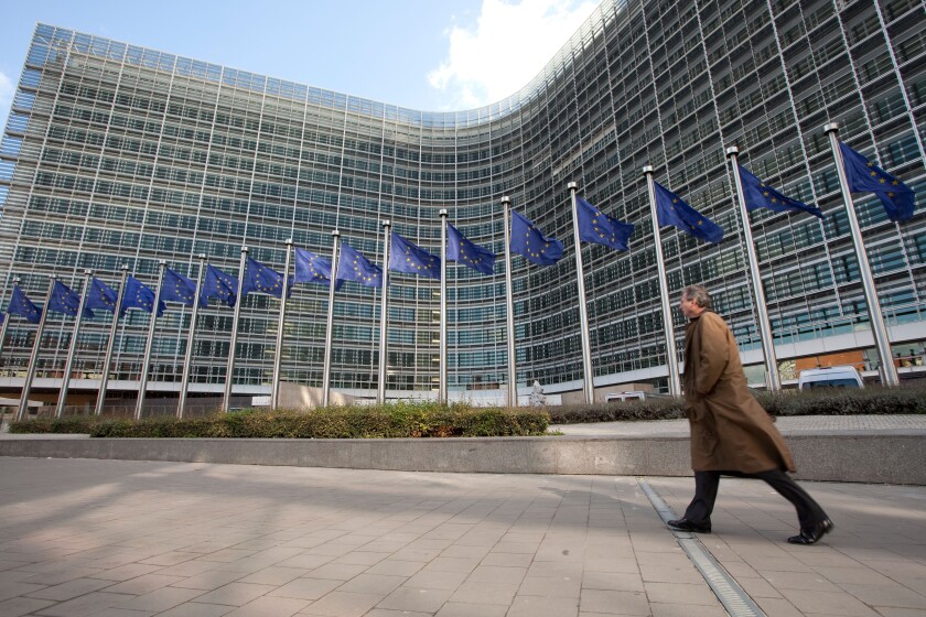 A man walks next to the european flags outside the Berlaymont building, the European Commission headquarters in Brussels