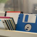 A box of old 3.5-inch floppy disks, colorful floppy disks for 8-bit computers from the 1990s, a collection of old computer games on floppy disks, the