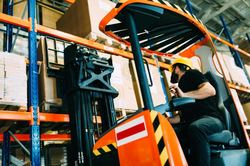 Warehouse worker doing logistics work with forklift loader