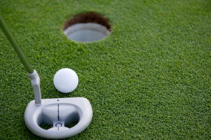 A very short putt in the game of golf on a putting green at a golf course with copy space