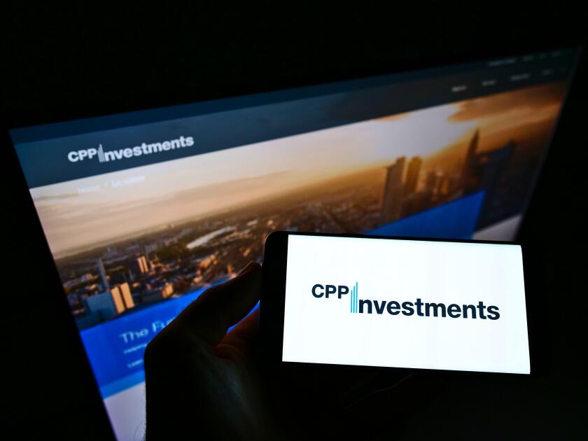 Person holding smartphone with logo of Canada Pension Plan Investment Board (CPPIB) on screen in front of website. Focus on phone display.