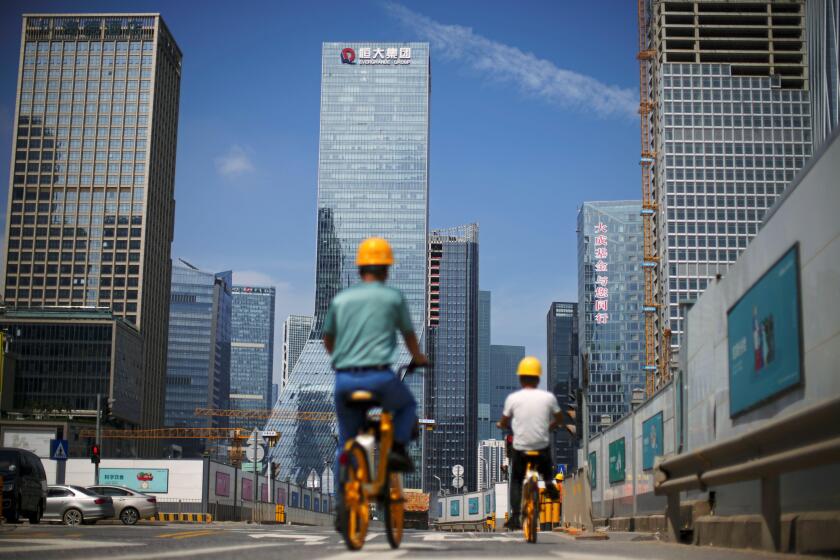 Men ride bicycles past construction sites near the headquarters of China Evergrande Group in Shenzhen, Guangdong province, China September 26, 2021. REUTERS/Aly Song