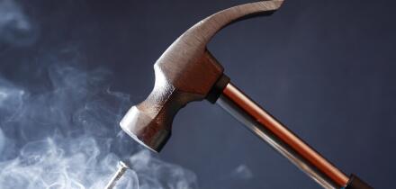 Work tool. Metal hammer above nail with smoke on nice dark background