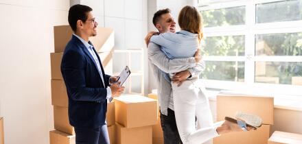Real Estate Agent And Happy Couple Moving Into New Home