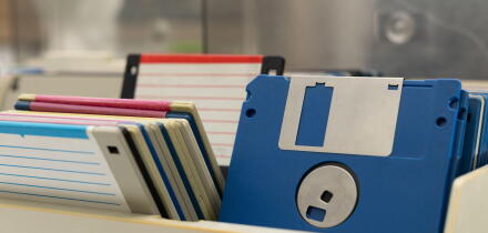A box of old 3.5-inch floppy disks, colorful floppy disks for 8-bit computers from the 1990s, a collection of old computer games on floppy disks, the