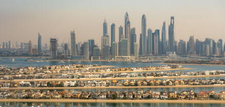 Aerial view of the luxury villas of the Palm Island and of the skyline of Dubai Marina, UAE. Hazy sky, pollution from the city. Futuristic skyline