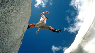 A hiker jumps over a crevasse on a glacier high in the Canadian Rockies in Banff National Park. Image shot 2003. Exact date unknown.