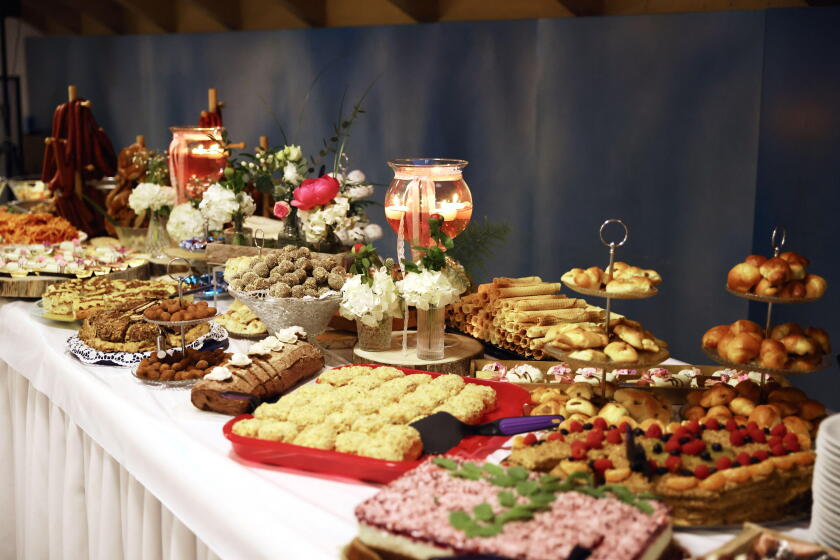 Lavishly decorated dessert buffet table with a variety of pastries, cookies, cakes, and sweets, beautifully arranged with floral decor.