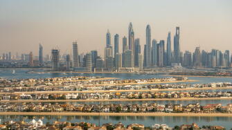 Aerial view of the luxury villas of the Palm Island and of the skyline of Dubai Marina, UAE. Hazy sky, pollution from the city. Futuristic skyline
