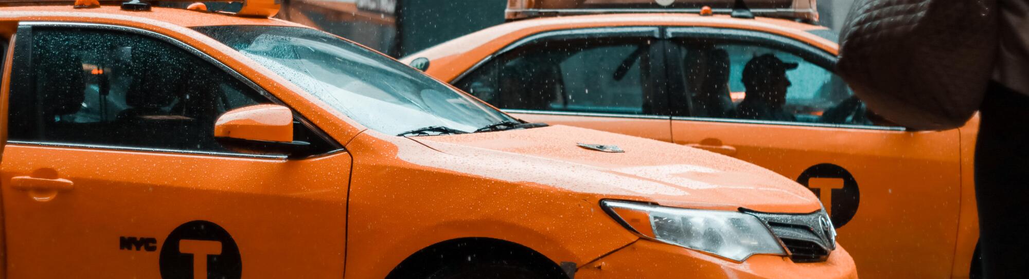New York: Yellow taxi cab speeds through busy traffic of downtown New York City on a rainy day. East 42nd strret, NY. Cloudy stormy weather