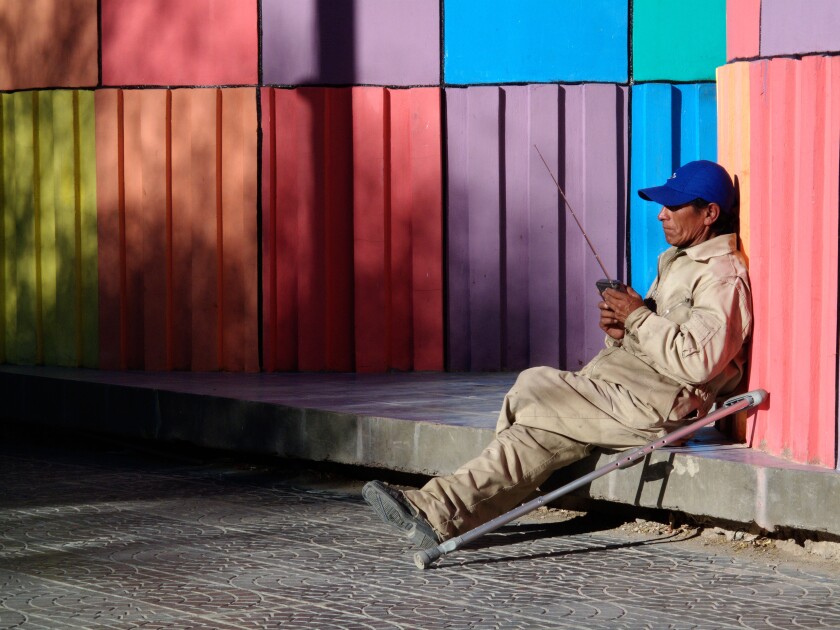 A man listens to a radio while sitting near a colourful monument in Uyuni near the Salar de Uyuni in Boliva