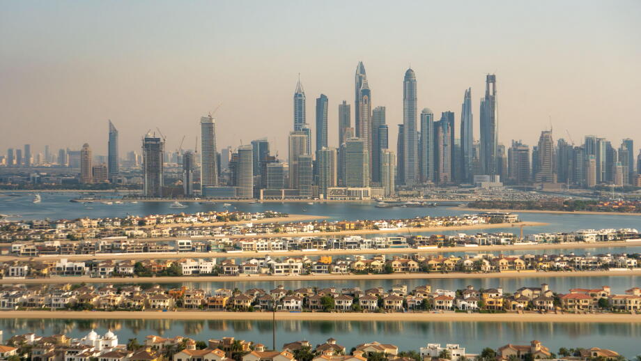 Aerial view of the luxury villas of the Palm Island and of the skyline of Dubai Marina, UAE. Hazy sky, pollution from the city. Futuristic skyline