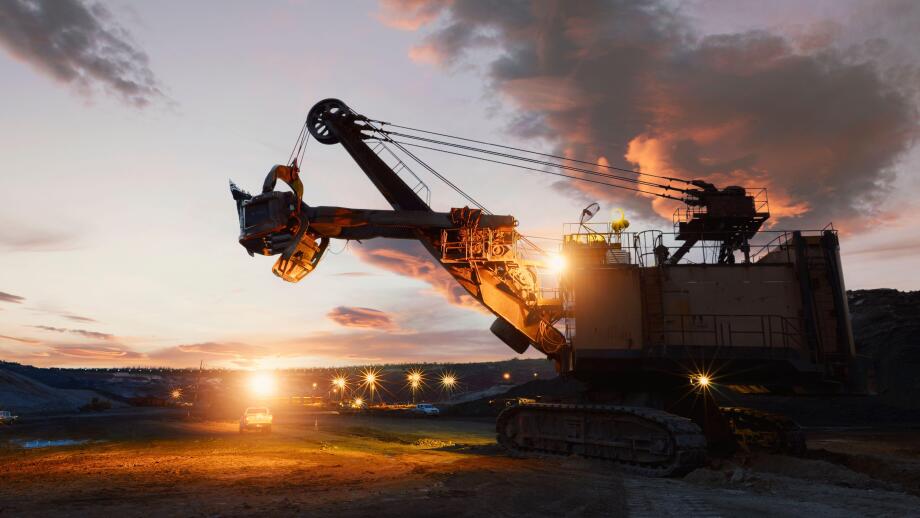 Silhouette of a mechanical digger at an iron ore mine at sunset, Thailand