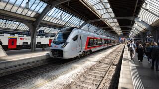 Zurich, Switzerland, April 23, 2026. Commuters walk along the platform at Zurich Main Station past a copper-colored SOB Traverso train parked under th