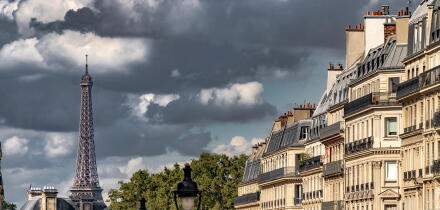 Dark clouds surround  The Eiffel Tower as seen  from Rue Soufflot , a street lined with impressive apartment buildings ,Paris ,France