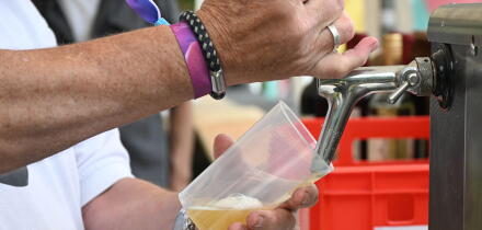 Beer is poured from a tap into a reusable plastic cup at a casual outdoor festival event, concept for sustainable open-air entertainment, fun and cold