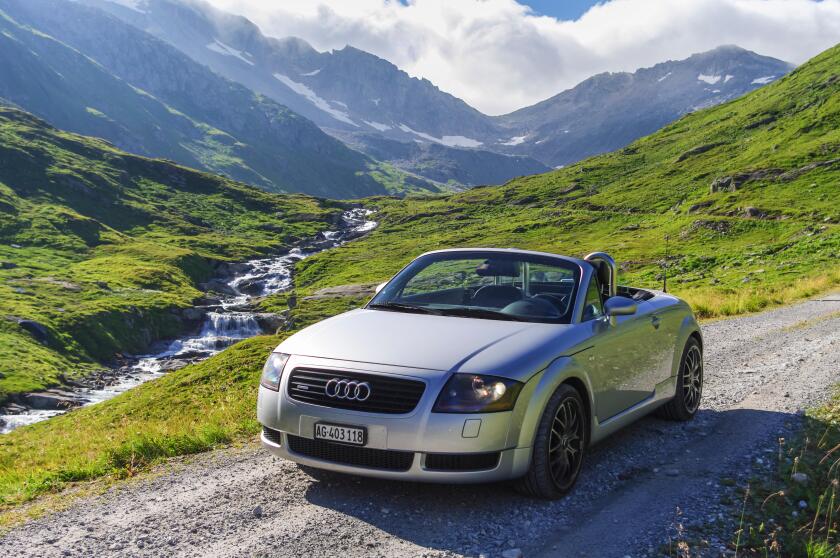 1999 Audi TT quattro roadster mark I (type 8N), silver metallic, roof retracted, on an unpaved Alpine road in Uri, Switzerland.