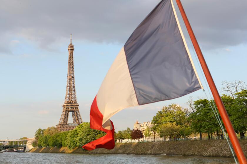 French flag and Eiffel Tower seen from River Seine, Paris, France.