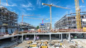 Large construction site with foundations, unfinished buildings and cranes