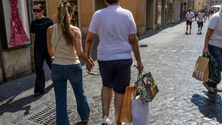Rome, Italy. July 4, 2026, Rome, Italy: The man of a tourist couple carries three paper bags after purchasing on the day the summer sales begin in Rome. End-of-season summer sales began today in all Italian regions, with the exception of the autonomous pr