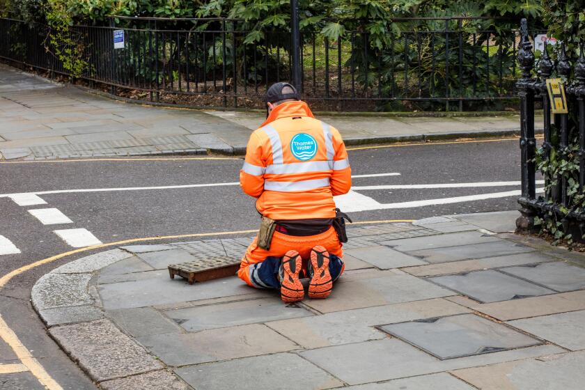 Thames Water employee at work in bright orange overalls in Kensington, London
