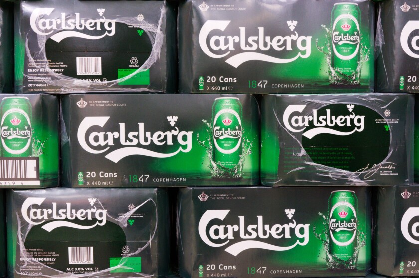 Boxes of Carlsberg beer cans stacked in a supermarket.