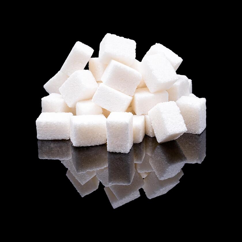 Cubes of white sugar from sugar beet with a real reflection on a black glossy background
