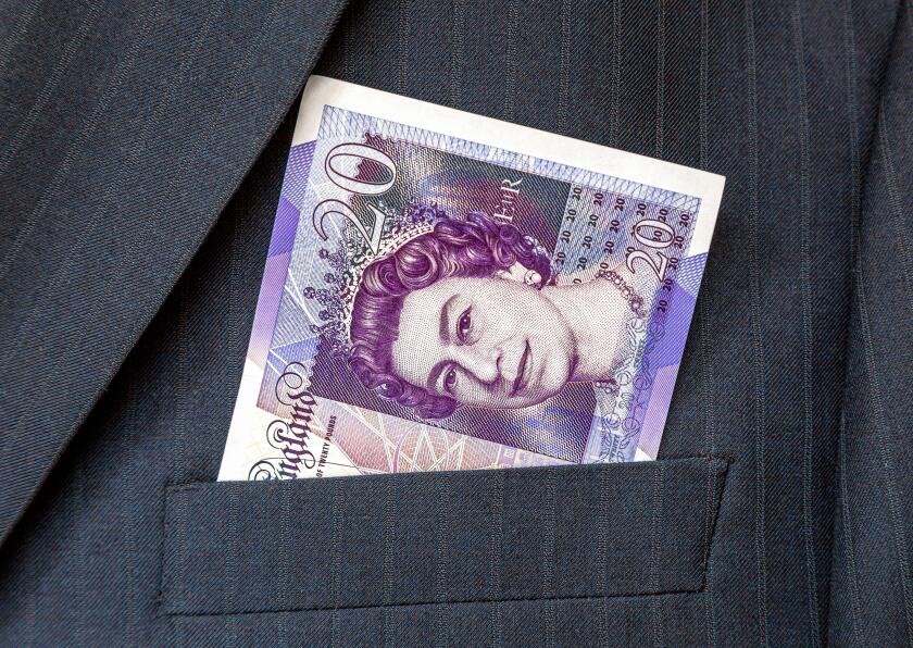 Banknotes of British pounds sticking out out of the businessman suit pocket. Money in the pocket of business suit