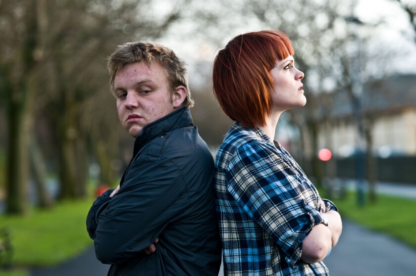 A young couple man and woman having an argument standing back to back not speaking to each other; sulking, not talking