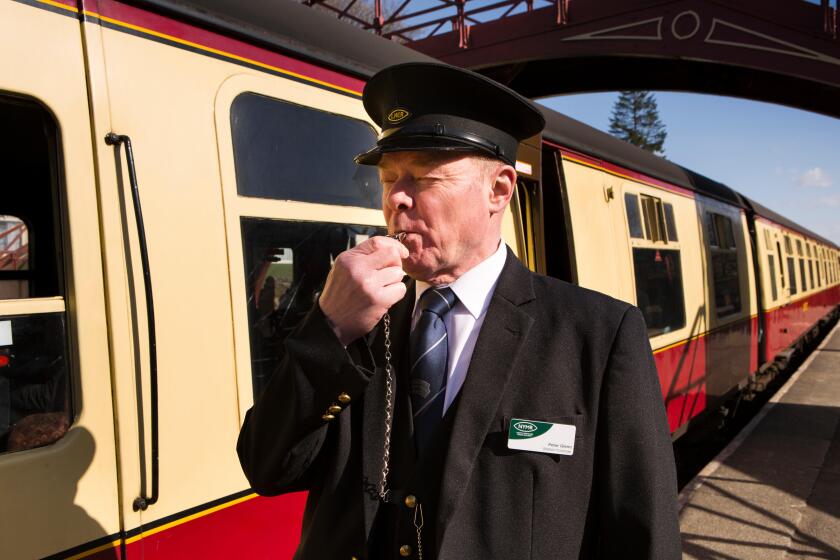 UK, England, Yorkshire, Goathland, North Yorkshire Moors Railway guard Peter Glenn, blowing whistle
