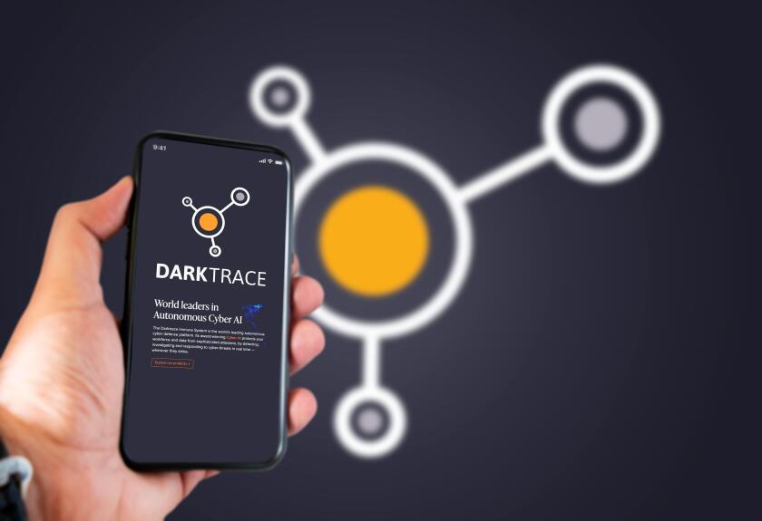 Cambridge, UK, May 2021: A hand holding a phone with the Darktrace company logo on the screen. Darktrace is an AI company that specialises in cyber de